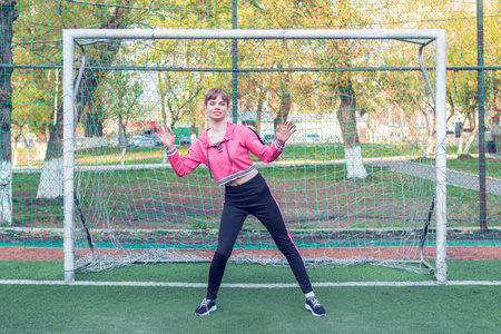 female goalkeeper stands with her arms spread to the side of a mini football goalの写真素材