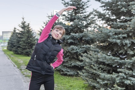 portrait of a beautiful woman involved in sports on a city street near the fir treesの写真素材