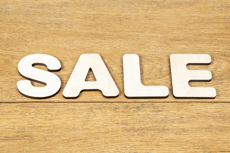 Word - sale, laid out in wooden letters on an old wooden tableの写真素材