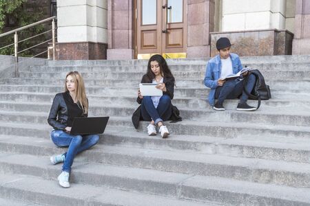 group of international students are studying sitting on the steps of the University of stairsの写真素材