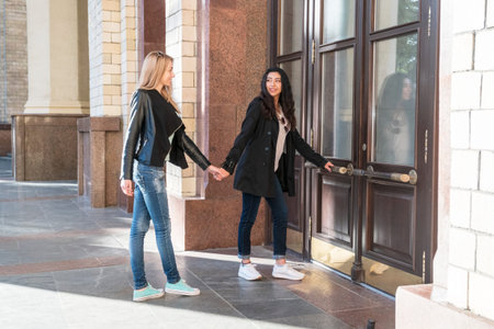two students holding hands enter the university building