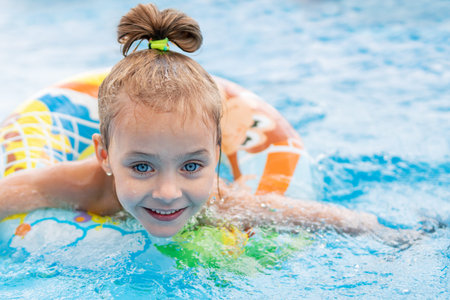 Little beautiful smiling girl swims on a rubber ring, close-upの写真素材