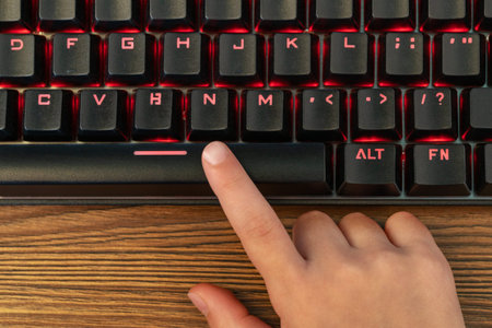 child index finger presses the spacebar on the black keyboardの写真素材