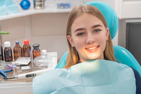 portrait of a beautiful smiling patient girl in a dental chairの写真素材
