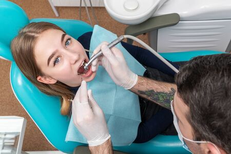 dentist drills upper tooth to patient lying in dental chairの写真素材