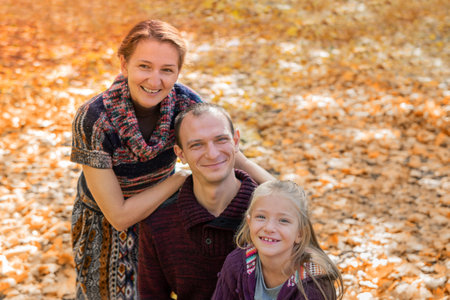 family portrait mother, father and daughter on a background of yellow leaves on an autumn day