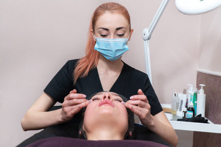 beautician massages the patient face in the eye area
