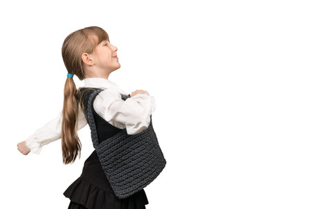 cheerful schoolgirl with a knitted bag goes waving hand isolated on white backgroundの写真素材