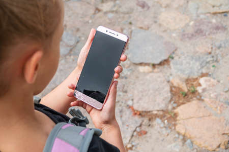 little girl holding a phone with broken screen while going to schoolの写真素材