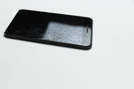 Mobile smartphone with broken screen on white background.