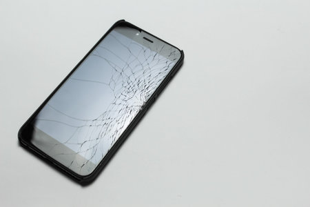 Mobile smartphone with broken screen on white background.
