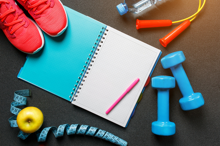 Notepad, a bottle of water, an apple, a skipping rope, dumbbells. Healthy diet, lifestyle, concept of dumbbells, exerciseの写真素材