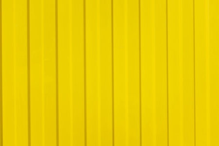 A corrugated fence of yellow metal sheets with screw. Texture of metal fence.の写真素材