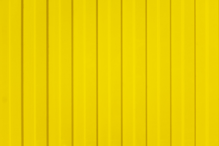 A corrugated fence of yellow metal sheets with screw. Texture of metal fence.の写真素材