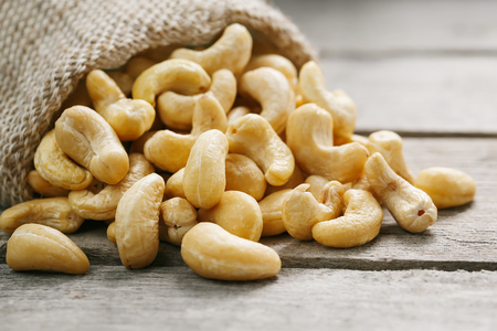 Cashew nuts in burlap bag on wooden gray background . Healthy foodの写真素材