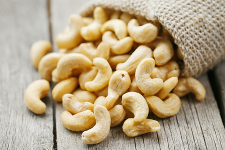Cashew nuts in burlap bag on wooden background . Healthy food. Indian nut, Anacardium westernの写真素材