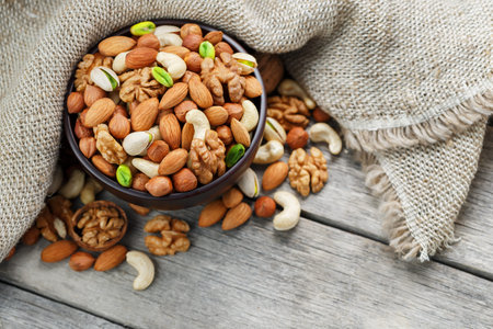 Wooden bowl with nuts on a wooden background, near a bag from burlap. Healthy food and snack,...