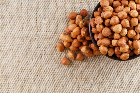 Peeled hazelnuts in a wooden, dark brown cup on a burlap cloth. Super Food, Raw.の写真素材