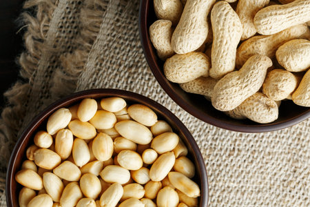 Peanuts in the shell and peeled closeup in a cup. Background with peanuts. Roasted peanuts in the...