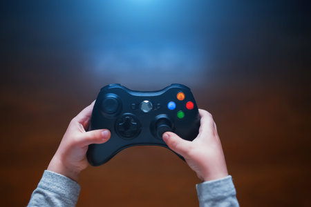 Video game controller in the hands of a child. In front of the TV in the evening, with blue light...