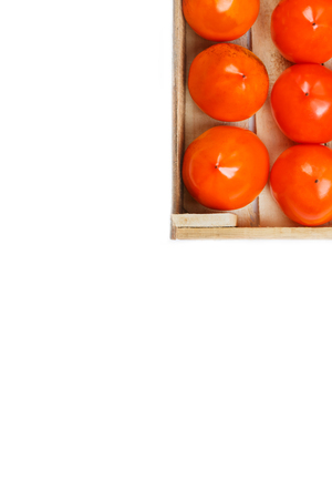 Persimmon fruit in the wooden box isolated on white.の写真素材