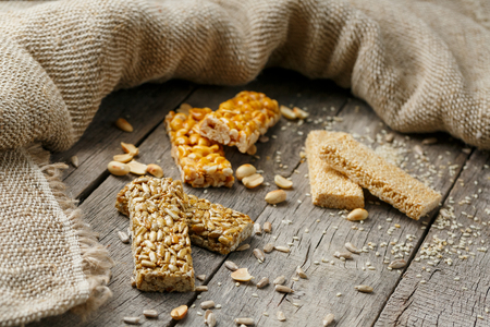 Assorted kozinaki, on old vintage background, with burlap fabric. Country style. Delicious sweets from the seeds of sunflower, sesame and peanuts, covered with shiny glaze. View from aboveの写真素材