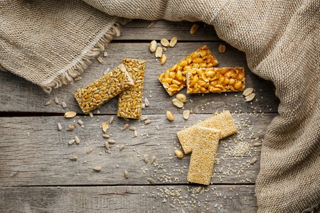 Assorted kozinaki, on old vintage background, with burlap fabric. Country style. Delicious sweets from the seeds of sunflower, sesame and peanuts, covered with shiny glaze. View from aboveの写真素材