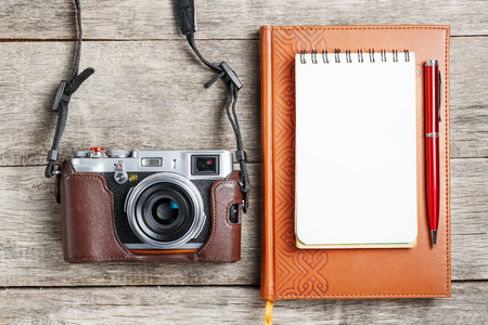 Classic camera with blank notepad page and red pen on gray wooden, vintage table with telephone and green flower. The concept of the list for the photographer in travels. Country style.の写真素材