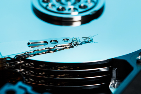 The mechanism from the inside of the disassembled hard drive from a computer, a hard drive with a mirror effect and a read head. Information on the Blue metallic carrier, repair service and operation PC computer, laptop. Macroの写真素材