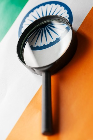 The Indian flag is visible through a magnifying glass. Spies and Observations for India India. Monitoring the state of India. War Terrorism Theft Conceptの写真素材