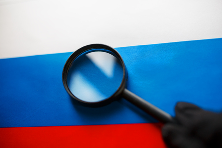 The flag of the Russian Federation is viewed through a magnifying glass. Spying and monitoring Russia. Monitoring the status of Russian. The concept of the danger of theft of military terrorismの写真素材