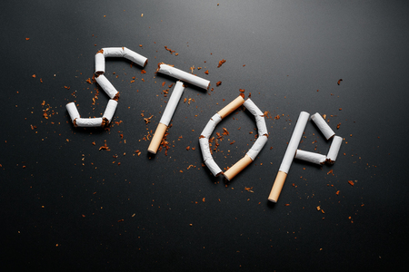 The inscription STOP from cigarettes on a black background. Stop smoking. The concept of smoking kills. Motivation inscription to quit smoking, unhealthy habit. Smoking as a deadly habit, nicotine poison, cancer and smokingの写真素材
