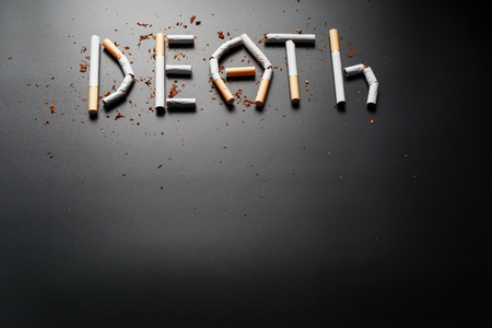 The inscription DEATH from cigarettes on a black background. Stop smoking. The concept of smoking kills. Motivation inscription to quit smoking, unhealthy habit. Smoking as a deadly habit, nicotine poison, cancer and smokingの写真素材