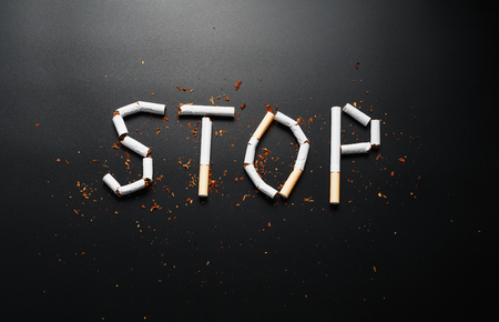 The inscription STOP from cigarettes on a black background. Stop smoking. The concept of smoking kills. Motivation inscription to quit smoking, unhealthy habit. Smoking as a deadly habit, nicotine poison, cancer and smokingの写真素材
