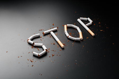 The inscription STOP from cigarettes on a black background. Stop smoking. The concept of smoking kills. Motivation inscription to quit smoking, unhealthy habit. Smoking as a deadly habit, nicotine poison, cancer and smokingの写真素材
