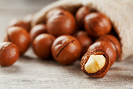 Macadamia nut on a wooden table in a bag, closeup, top view. Healthy productの写真素材