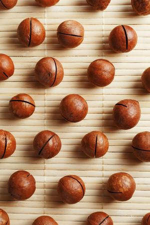 Flat composition with Australian macadamia nuts on bamboo light background. Patterns, repetitions. View from aboveの写真素材