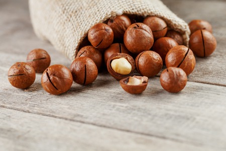 Macadamia nut on a wooden table in a bag, closeup, top view. Healthy productの写真素材