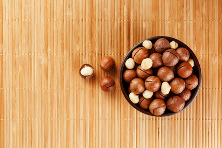 Macadamia nut on bamboo texture, concept of superfoods and healthy food. Overhead or top view shotの写真素材