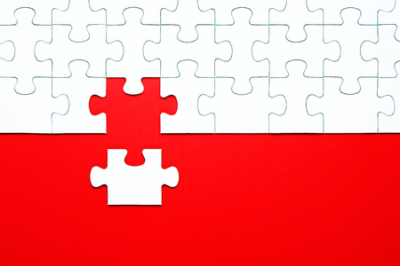 White puzzle pieces on a red background separatedの写真素材