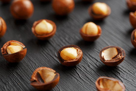 Purified and shell repeats macadamia nuts on black textural stone background. Healthy eating conceptの写真素材