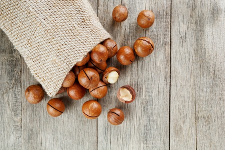 Macadamia nut on a wooden table in a bag, closeup, top view. Healthy productの写真素材