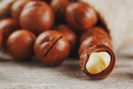 Macadamia nut on a wooden table in a bag, closeup, top view. Healthy productの写真素材