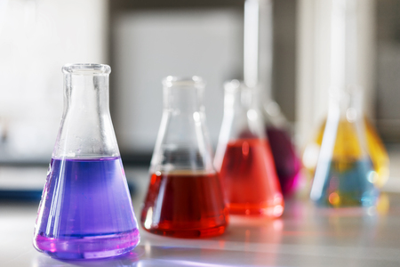 Chemical laboratory flask with blue purple-pink liquid stand on the table. Chemicals of liquid tests of test development, substances, poisons, additives, stabilizers, flavors, cleaning the houseの写真素材