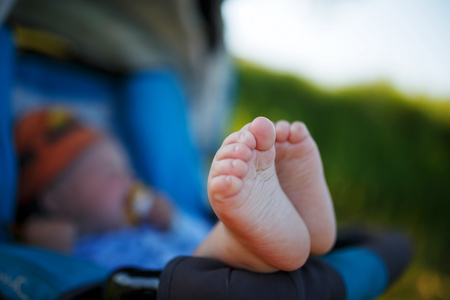 Cute, funny gentle heels of a child against the background of a lying in a stroller. Cheerful baby with cute heels in a stroller in natureの写真素材