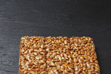 Useful snacks. Fitness diet food. Boletchik from kozinaki sunflower seeds, energy bars. Black textural background Top view. Copy space, low keyの写真素材
