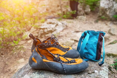 Orange climbing shoes and magnesium in a blue bag stand on a stone. Rock Climbing Clothingの写真素材