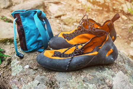 Orange climbing shoes and magnesium in a blue bag stand on a stone. Rock Climbing Clothingの写真素材