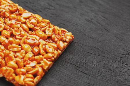 Golden boletus kozinaki from roasted peanut beans energy bars. Black textural background, top view. Copy space, useful snacks. Fitness diet food, super food. In low keyの写真素材