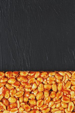 Golden boletus kozinaki from roasted peanut beans energy bars. Black textural background, top view. Copy space, useful snacks. Fitness diet food, super food. In low keyの写真素材